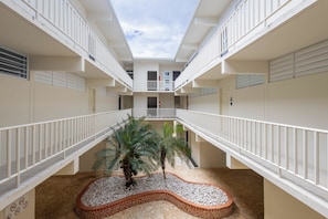 A multi-level atrium with a central garden, white railings, and a clear sky view.