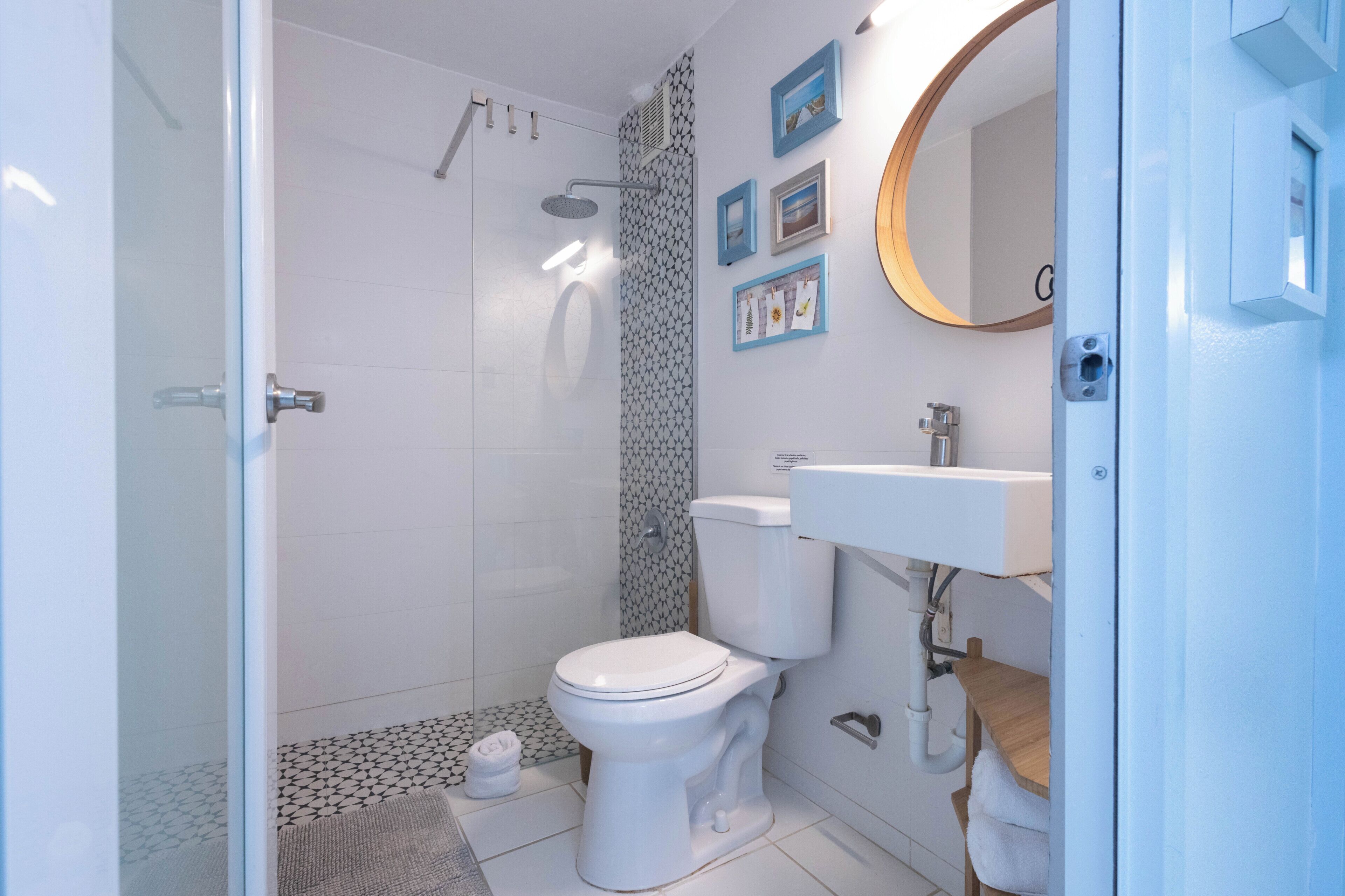 Un baño moderno con cabina de ducha de vidrio, inodoro blanco y lavamanos con encimera de madera.