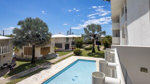Ein Pool mit blauem Himmel, Palmen und einem weißen Gebäude mit Balkonen.