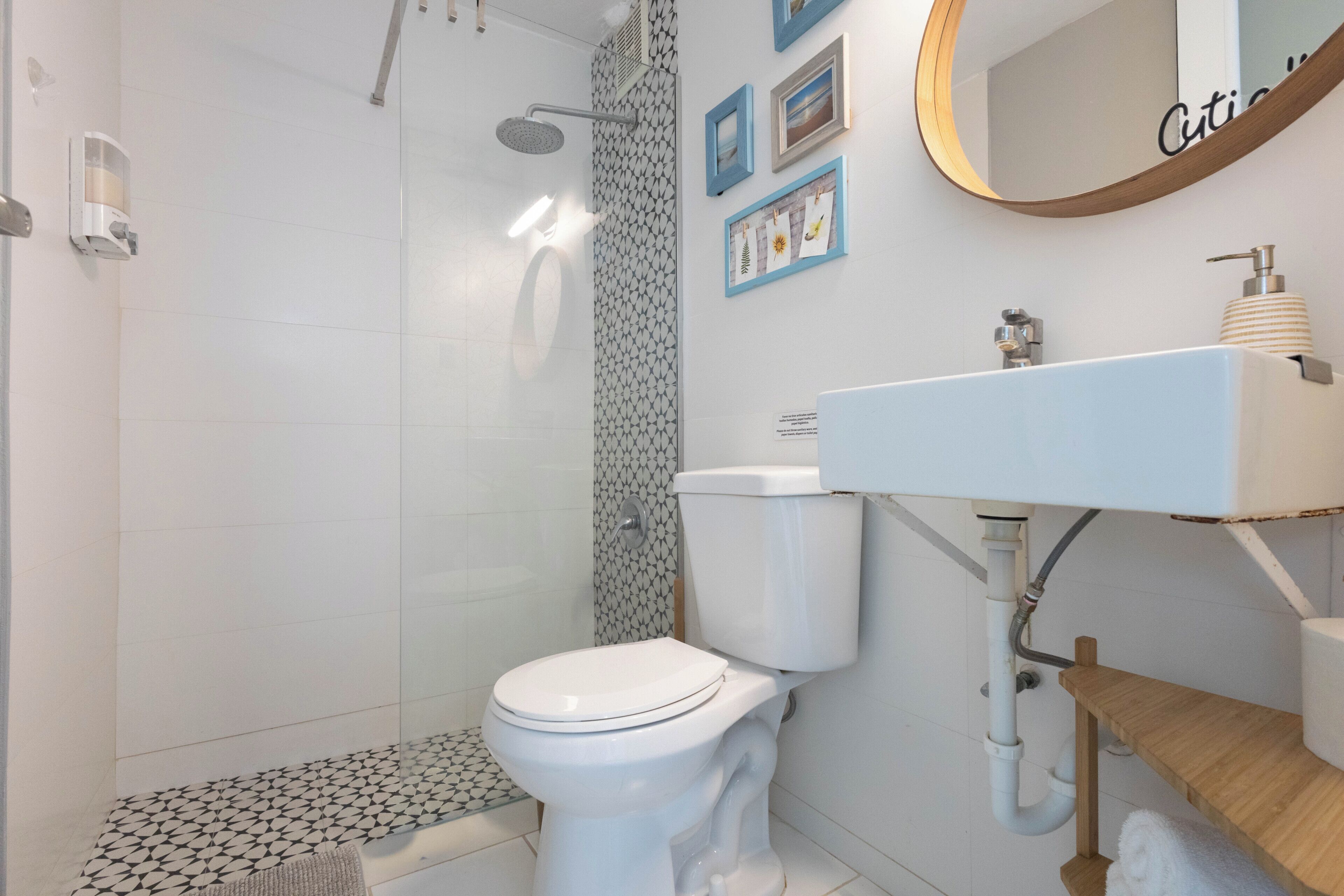 A bathroom with a shower, toilet, sink, and a mirror.