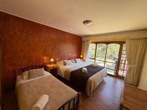 A hotel room with two beds, a large window with curtains, a ceiling light, and a wooden floor. - Vertientes de Elqui (Vicuña)
