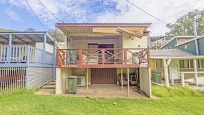 A two-story building with a balcony, a covered porch, and a garage. - Quaint River Shack (Caloote)