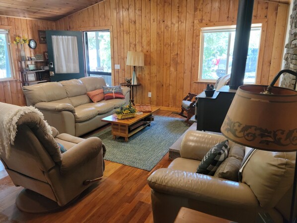 A cozy cabin-style room with a leather sofa, a recliner, and a wooden coffee table.