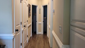 A hallway with wooden flooring, white doors, and recessed ceiling lights.