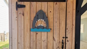 A wooden door with a shark mouth cutout and a blue wave design below it.