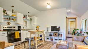 Una cocina moderna con armarios blancos, una estufa y un comedor con mesa y sillas.