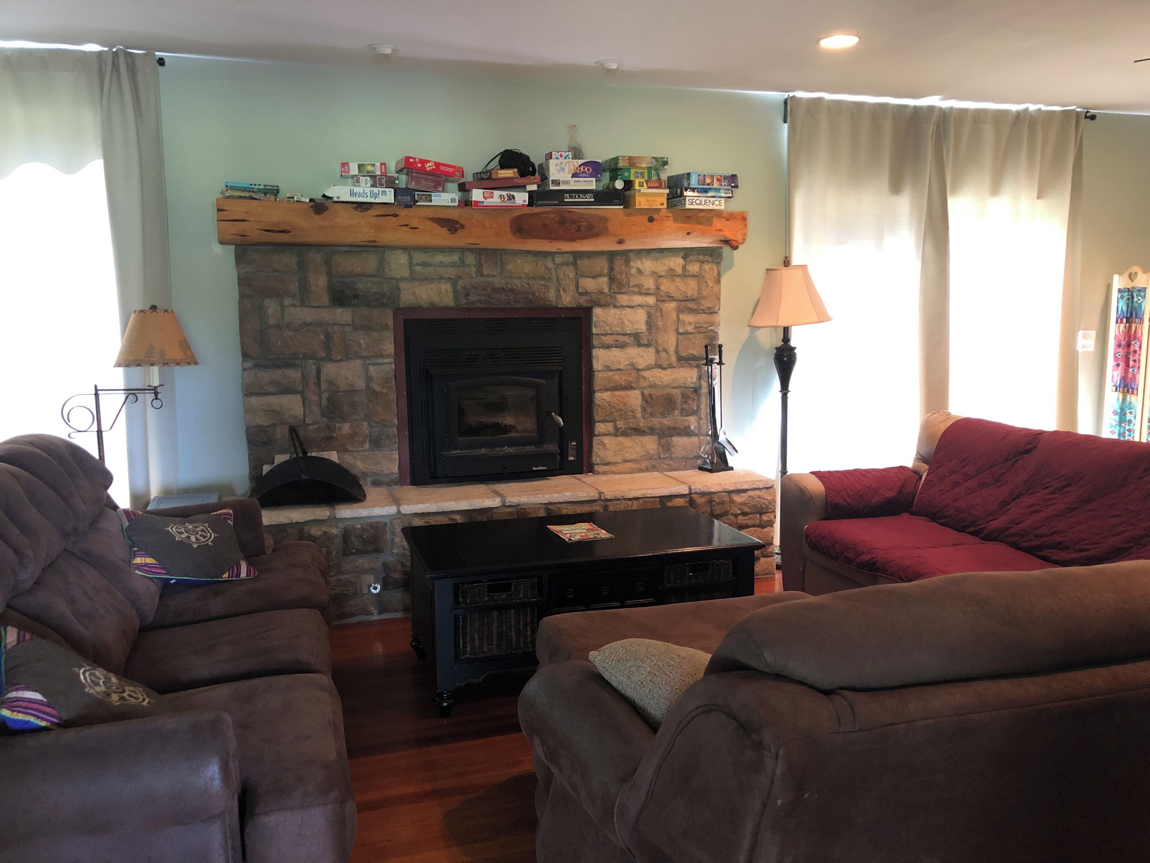 A living room with a stone fireplace, two couches, a coffee table, and a lamp.