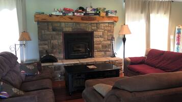 A living room with a stone fireplace, two couches, a coffee table, and a lamp.