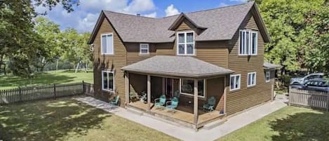 A two-story house with a covered porch and a fenced backyard.