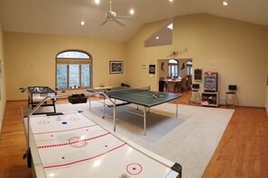 A spacious room with a ping pong table, a foosball table, and a small table tennis table.
