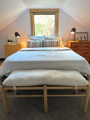 Une chambre à coucher avec un lit, deux tables de chevet, une fenêtre et un plafond.