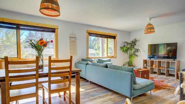 A modern living room with a wooden dining table, blue sofa, and a television. - Lovely Spacious Home In Downtown White Salmon (White Salmon)