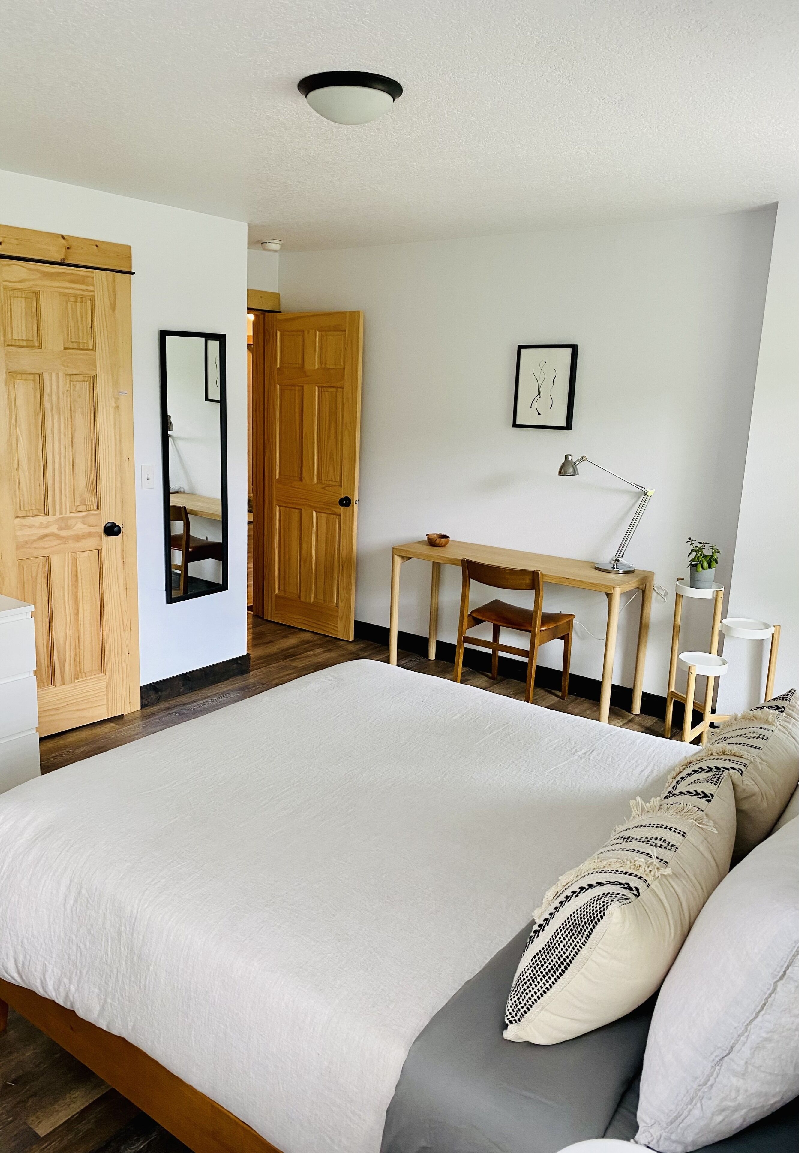 A bedroom with a large bed, wooden wardrobe, desk, and chair.