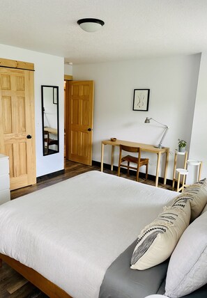 Een slaapkamer met een groot bed, een houten garderobe, bureau en stoel.