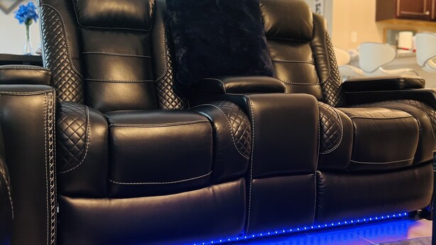 A black leather sofa with quilted detailing and a black cushion, accompanied by a blue LED light strip. - Brand New Construction 🏠 Resort style Getaway (Jacksonville)