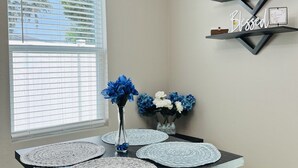 A dining area with a table, benches, a chandelier, and wall-mounted shelves with decorative items. - Brand New Construction 🏠 Resort style Getaway (Jacksonville)