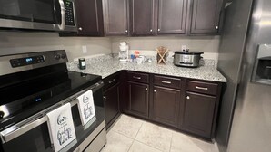 A kitchen with dark wood cabinets, stainless steel appliances, and a granite countertop. - Brand New Construction 🏠 Resort style Getaway (Jacksonville)