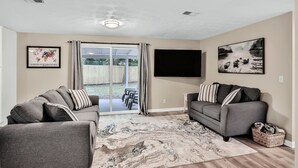 A living room with two grey sofas, a patterned rug, and a flat-screen TV mounted on the wall. - ⭐️Stylish 3/2 🏡 fully renovated in Orange Park⭐️ (Orange Park)