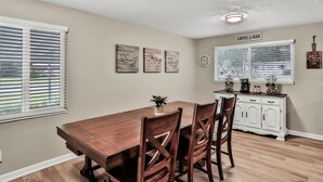 A dining area with a wooden table and chairs, a small plant, and a coffee bar sign on the wall. - ⭐️Stylish 3/2 🏡 fully renovated in Orange Park⭐️ (Orange Park)