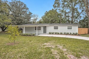 A single-story house with a front porch, a small front yard, and a wooden fence.