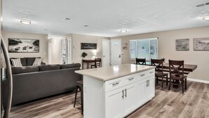 A modern kitchen with a central island, white cabinetry, and a dining area with wooden chairs and a table. - ⭐️Stylish 3/2 🏡 fully renovated in Orange Park⭐️ (Orange Park)