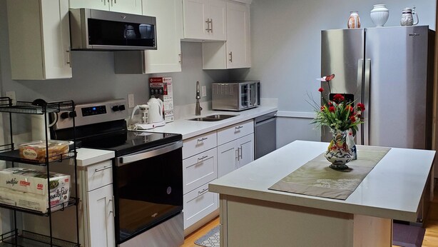 A modern kitchen with white cabinets, stainless steel appliances, and a central island.