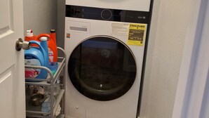 A compact laundry room with a front-loading washer and dryer stacked vertically.