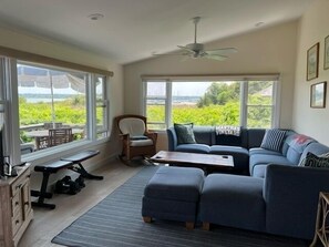 Relax in a spacious living area with a sofa facing a window overlooking lush greenery and water.