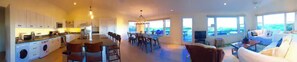 Experience a spacious home with a central open-plan layout, featuring a modern kitchen, dining area, and cozy living room with a large window offering a view of the outdoors.