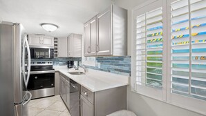 A modern kitchen with stainless steel appliances, white cabinetry, and a tiled backsplash.