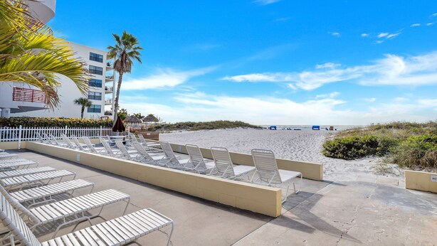 A beachside hotel with lounge chairs and a pool area.