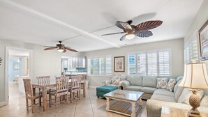 A spacious living room with a dining area, a sofa set, and a ceiling fan.