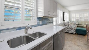 A kitchen with a double sink, white cabinets, and a tiled backsplash.