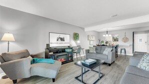 A modern living room with a fireplace, grey sofas, a coffee table, and a kitchen area in the background. - 3 Pools, Year Round Indoor pool and Hot tub, Gorgeous and Fun/10th Tee, WALK IN (Branson)