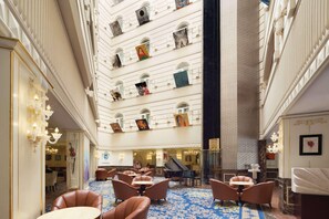 A hotel lobby with multiple floors, a grand staircase, and a piano. - Grand Regency Doha, Trademark Collection Wyndham (Doha)