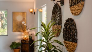 Una habitación con una planta en maceta, cestas tejidas colgadas en la pared y un cuadro.
