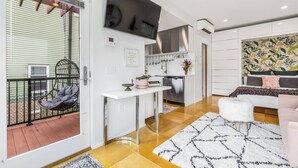 A modern kitchen with a flat-screen TV, a dining area with a white table, and a living room with a sofa and decorative pillows. - Not so tiny house with full kitchen & patio swing (Pittsburgh)