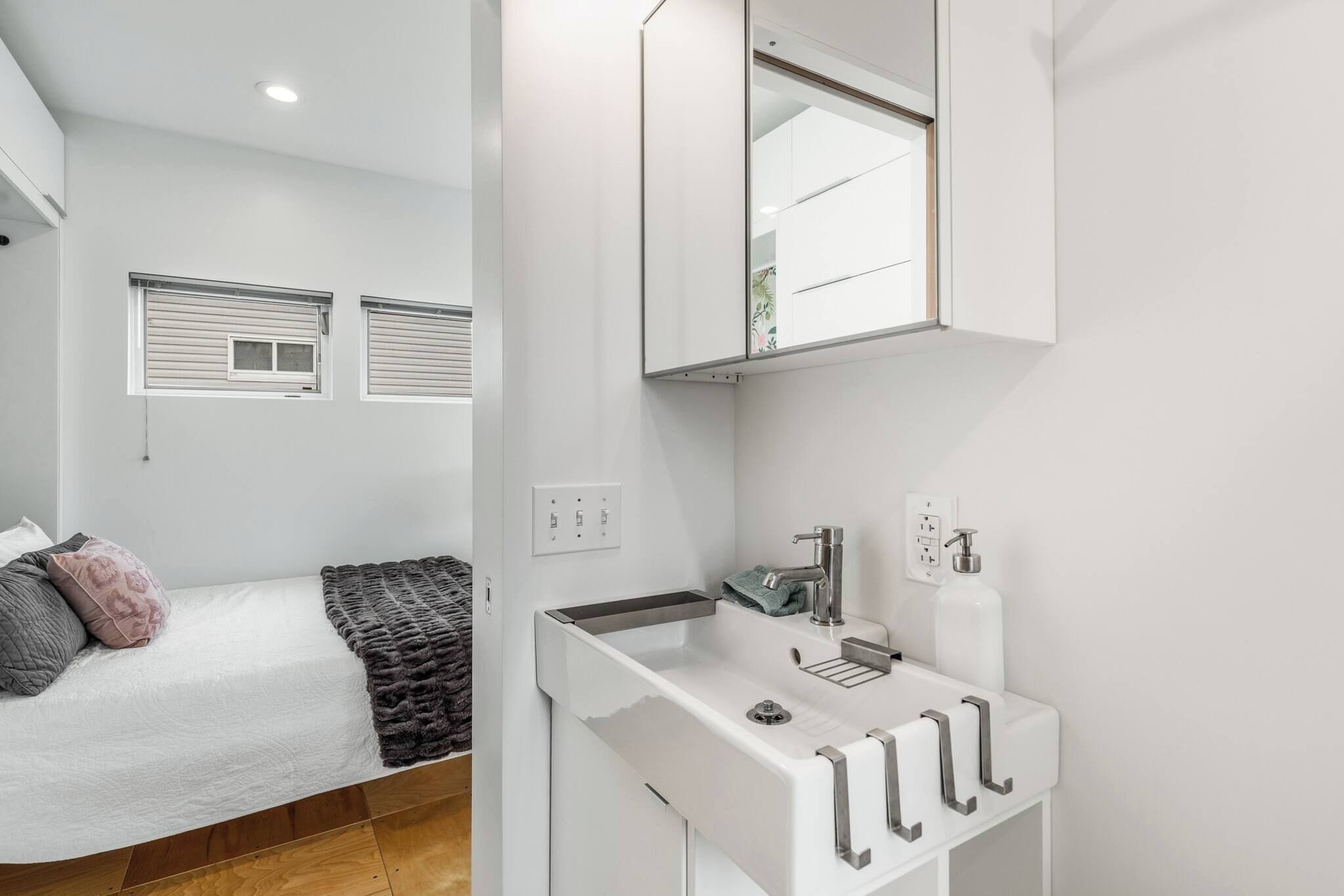 Un baño moderno con un lavamanos blanco, un espejo y un perchero para toallas.