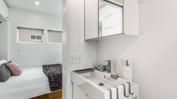 Un baño moderno con un lavamanos blanco, un espejo y un perchero para toallas.