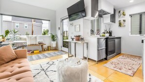 A modern kitchen with a built-in oven, a dining area with a white table and chairs, and a cozy seating area with a sofa and ottoman. - Not so tiny house with full kitchen & patio swing (Pittsburgh)