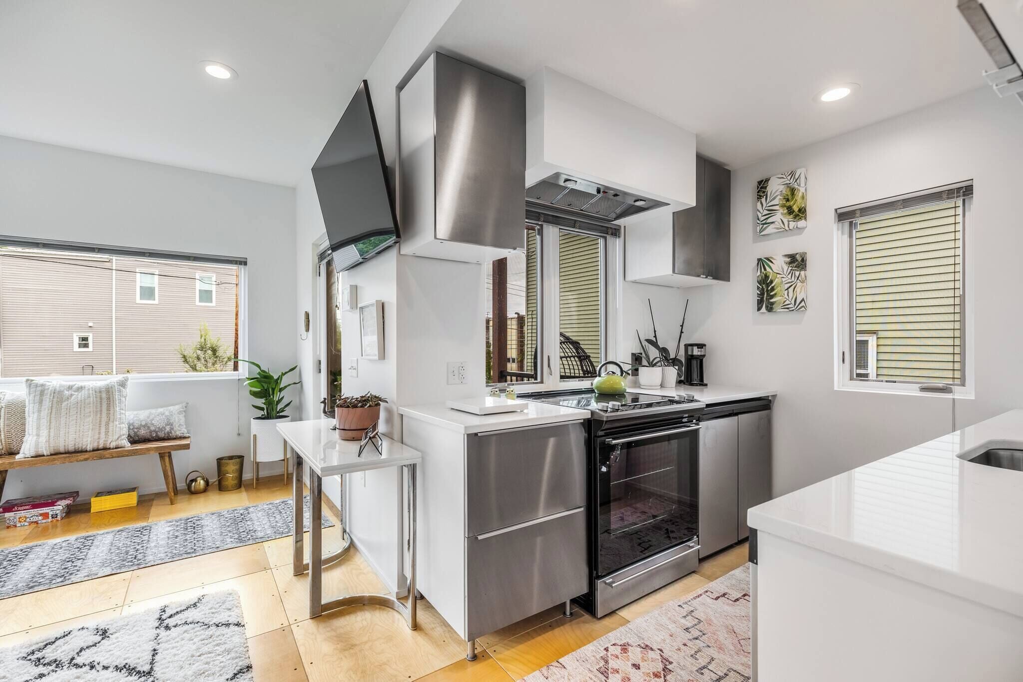 A modern kitchen with stainless steel appliances, a built-in oven, and a window with blinds.
