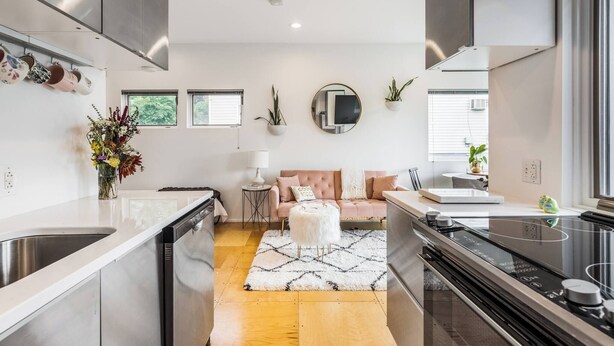 A modern kitchen with a central island, stainless steel appliances, and a seating area with a sofa and coffee table. - Not so tiny house with full kitchen & patio swing (Pittsburgh)