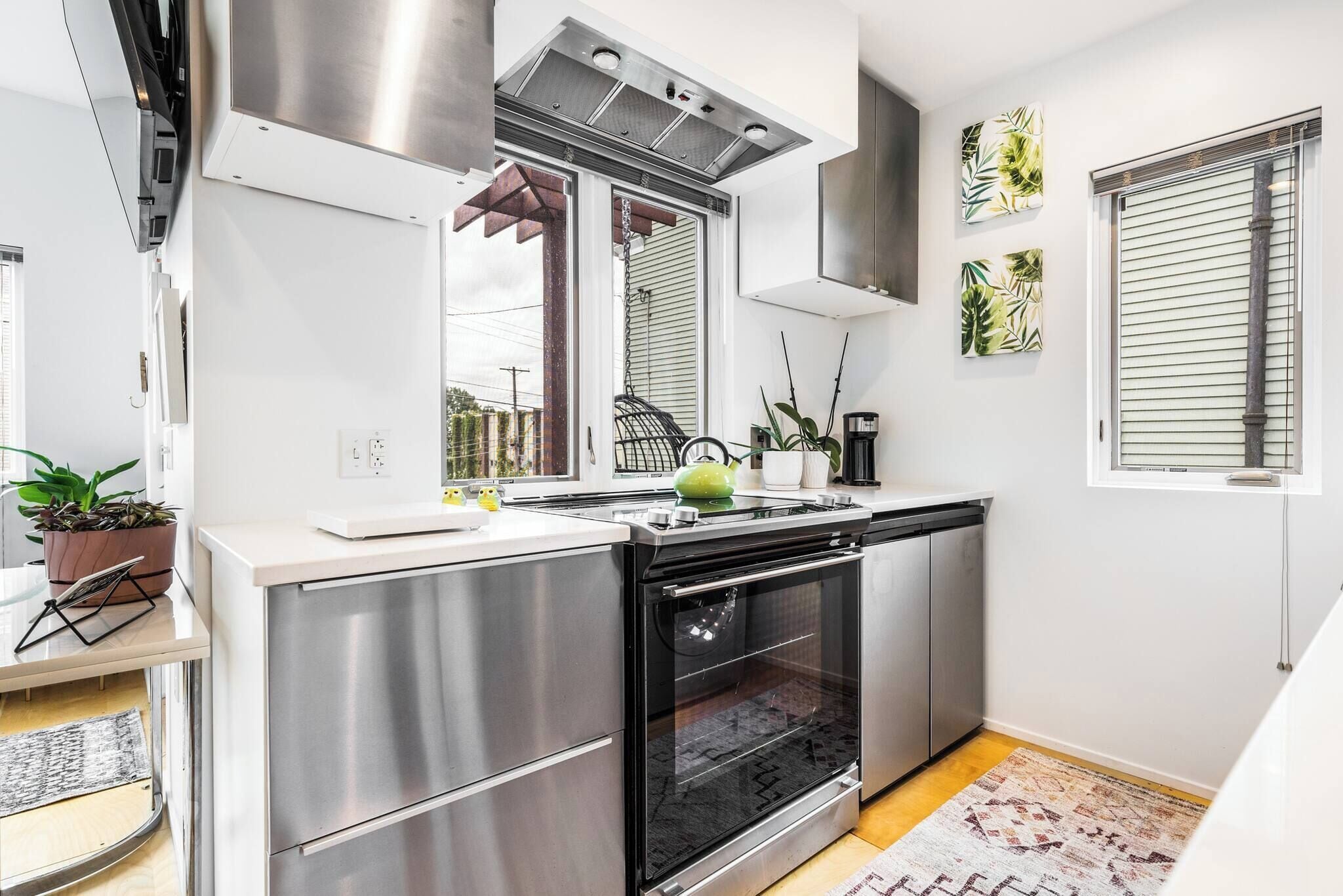 A modern kitchen with stainless steel appliances, a built-in oven, and a window with blinds.