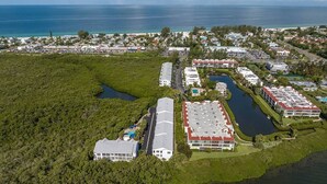 Eine Luftaufnahme eines Küstenresorts mit mehreren Gebäuden, einer Marina und einer großen Wasserfläche.