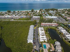 Luchtbeeld van een kustplaatsje met een jachthaven, een groot hotel met meerdere gebouwen, en een dicht bosgebied.
