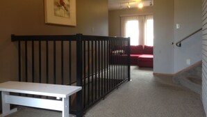 Ein Zimmer mit einer weißen Bank, einem schwarzen Geländer, einem roten Sofa und einem Gemälde an der Wand.