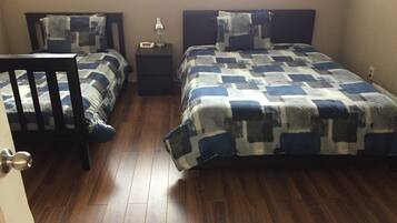 A bedroom with two beds, a nightstand, a chair, and a window.
