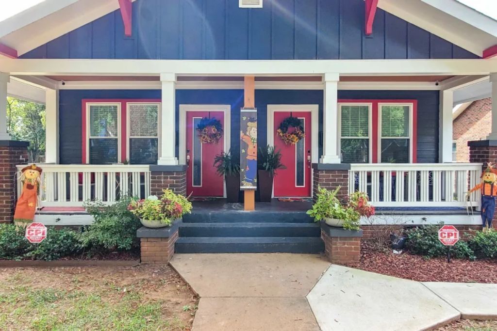 A house with a porch, red doors, and Halloween decorations.