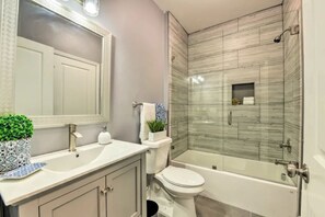 Une salle de bain avec un lavabo blanc, des toilettes et une douche séparée par une paroi de verre.