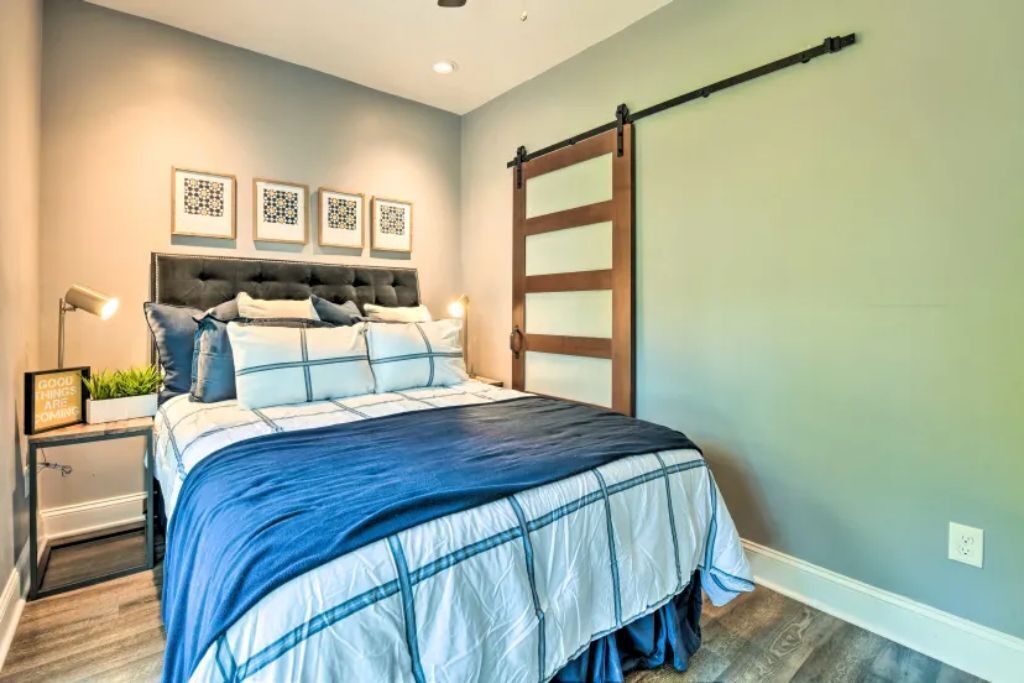 Une chambre à coucher comprenant un lit, des tables de chevet, une étagère fixée au mur et une porte coulissante.